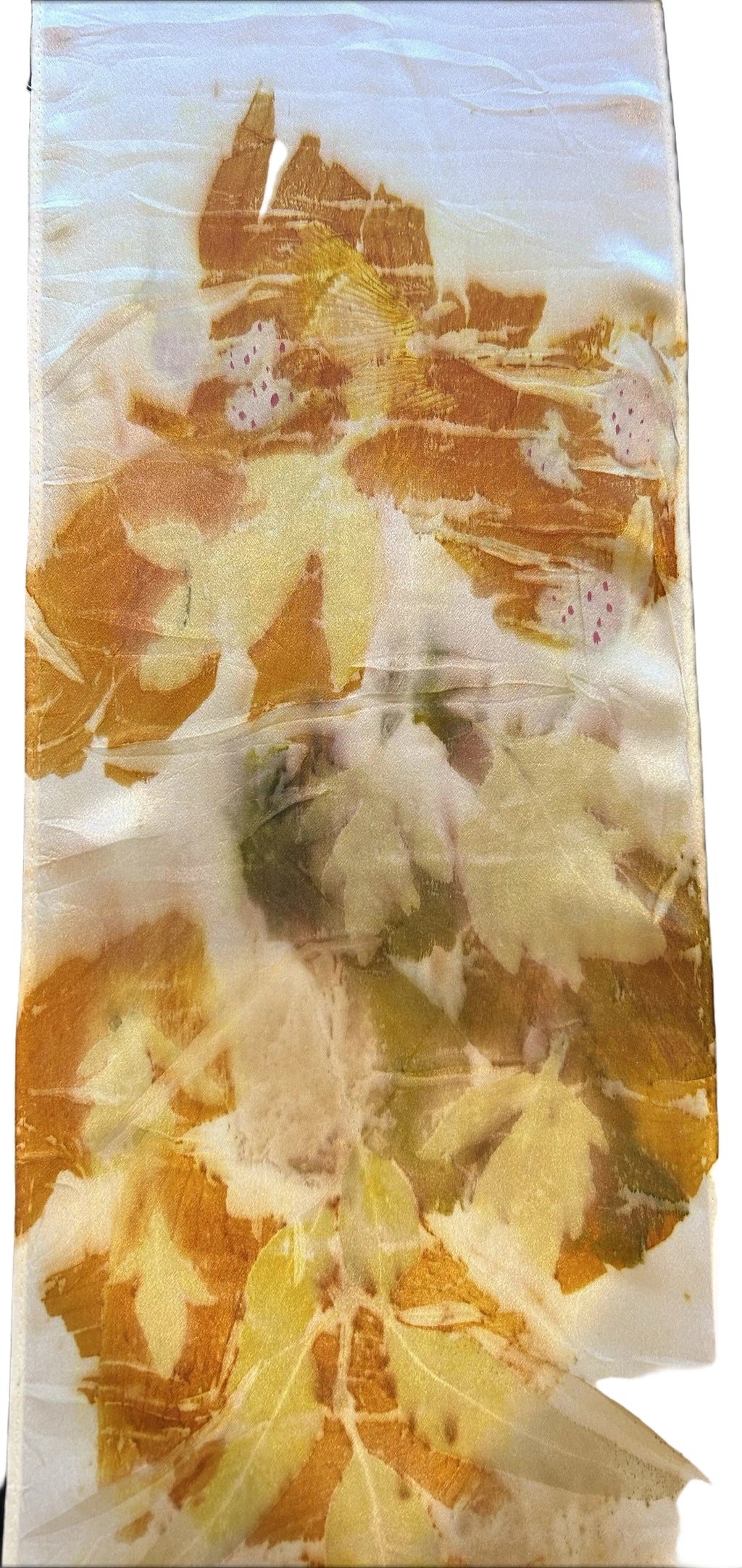 A rectangular white fabric item, likely a napkin or small tablecloth, featuring a marbled pattern with orange, yellow, and green leaf-like inclusions, photographed flat against a black background.